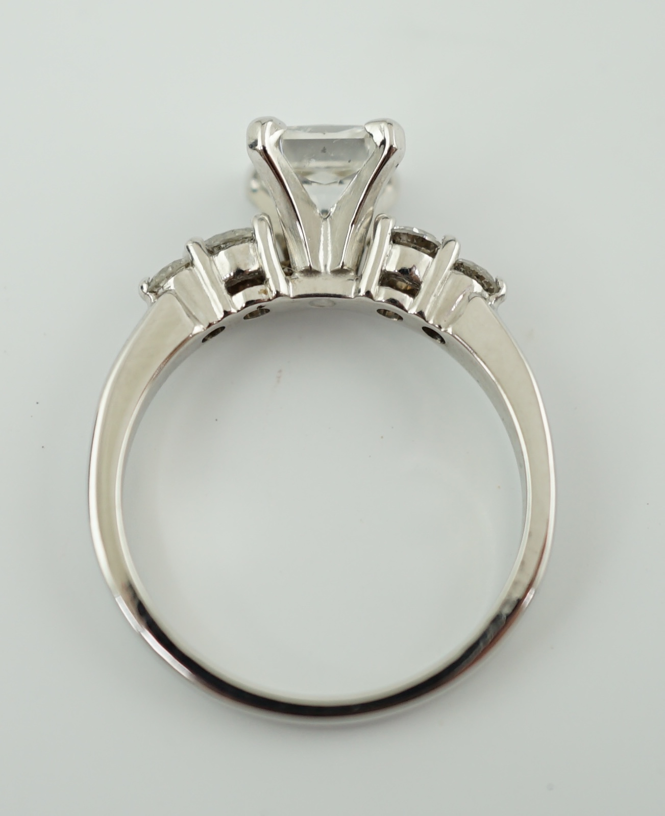 A modern 14k white gold and single stone diamond set ring, with four stone diamond set shoulders